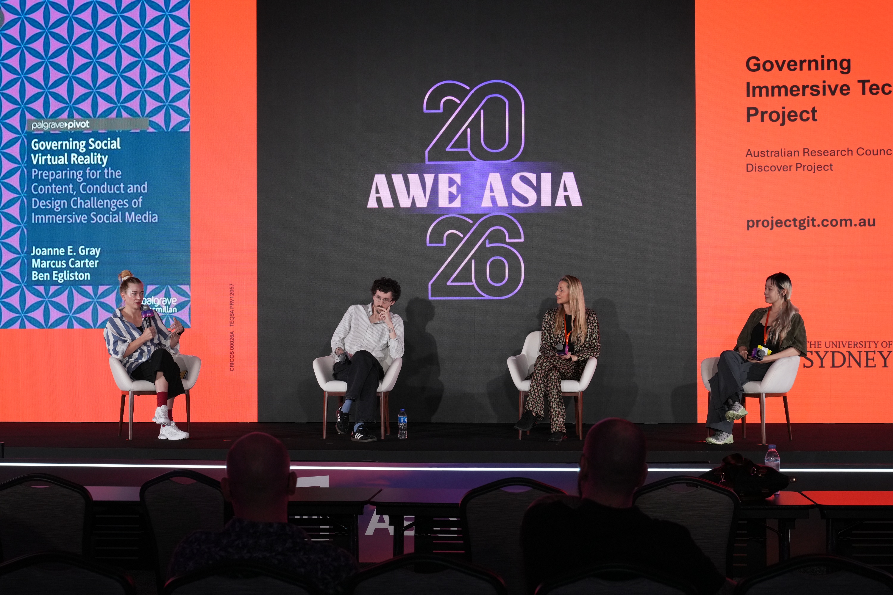 Four people sitting in a row on stage with the AWE Asia 2026 logo projected behind them